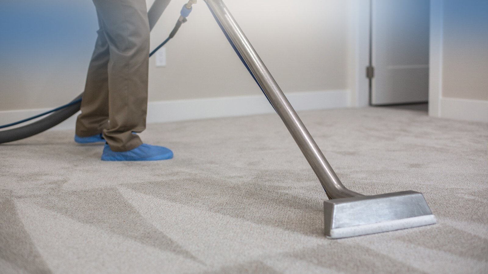 Technician steam cleaning a carpet in a home